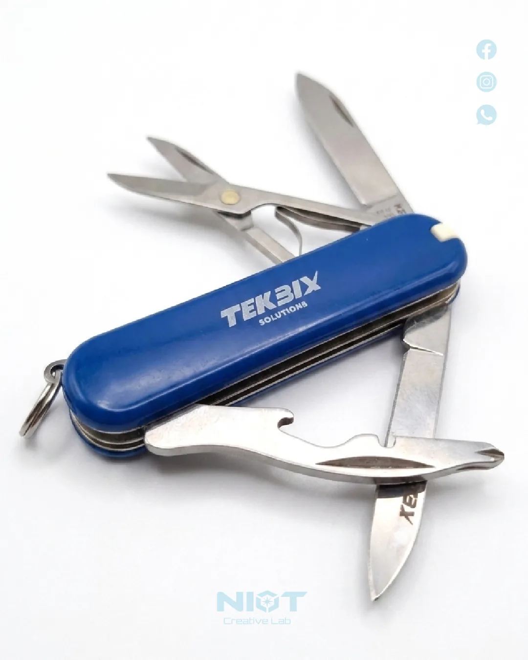 Navaja Victorinox azul TEKBIX con grabado láser corporativo, abierta mostrando todas sus herramientas sobre fondo blanco.
